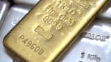 A one kilogram gold bar sits on top of silver bars.