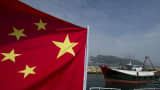 A fishing boat (R) sails past another boat flying a Chinese flag in the East China Sea