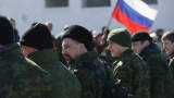 A unit claiming to Cossack and other citizen pro-Russian volunteers arrive to take up position outside a Ukrainian miltary base where heavliy-armed unidentifed soldiers have surrounded Ukrainian soldiers inside as Russian flag flies behind in Crimea on March 3, 2014 in Perevalne, Ukraine.