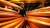 An employee inspects coils of copper rod.