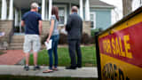 An agent, right, stands with potential home buyers outside a previously owned home in Mackinaw, Illinois.
