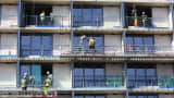 Construction workers stand on apartment balconies at the Lexicon residential building site in London, UK