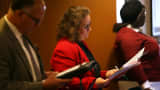 Job seekers fill out applications before the start of a career fair.