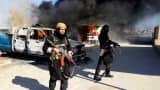 This undated file image posted on a militant website on Jan. 4, 2014, which is consistent with other AP reporting, shows Shakir Waheib, a senior member of the al-Qaida breakaway group Islamic State of Iraq and the Levant (ISIL), left, next to a burning police vehicle in Iraq's Anbar Province.