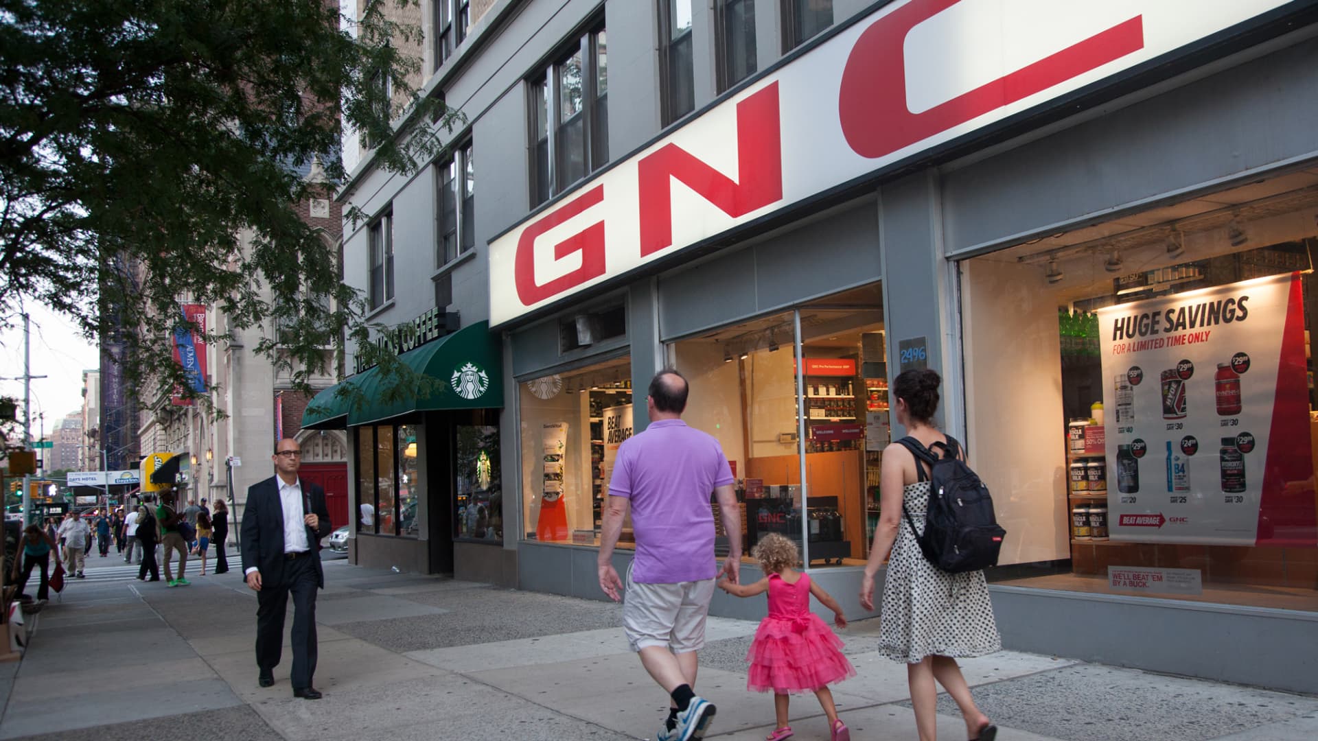 Pedestrians walk by a GNC store in New York.