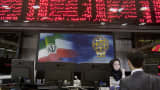 A trader speaks with a stock market official beneath the electronic board at the Tehran Stock Exchange, Sept. 15, 2010.