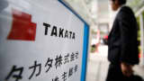 A man walks past a sign board of Japanese auto parts maker Takata Corp's Annual General Meeting in Tokyo June 26, 2014.