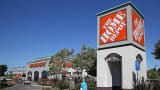 People walk by a sign in front of a Home Depot store in El Cerrito, Calif.