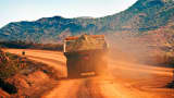 Iron ore dump truck going down dirt road