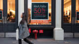 A pedestrian passes by a Black Friday discount sign at a Joe Fresh retail store in New York.