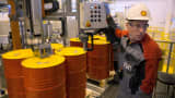 An employee holds a control panel as barrels are filled with lubricant oil ahead of shipping at Royal Dutch Shell lubricants blending plant in Torzhok, Russia.