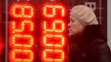 A woman walks past a board listing foreign currency rates against the Russian ruble outside an exchange office in Moscow on December 16, 2014.