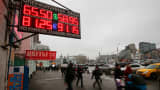 People walk past boards showing currency exchange rates in Moscow, December 17, 2014.