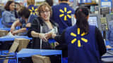 Employees assist shoppers at the check out counter of a Walmart store in Los Angeles.