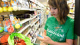 A shopper for Instacart studies her smart phone as she shops for a customer at Whole Foods in Denver.