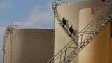 Workers walk down the stairs of an oil storage tank at the Musket Corp. Windsor Crude Terminal in Windsor, Colorado.