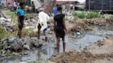 People walk past shanty homes at Badia East slums in Lagos.