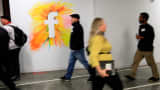 Employees walk past the company logo at Facebook offices in Menlo Park, California.