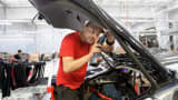 A worker installs interior trim on a Telsa Model S sedan.