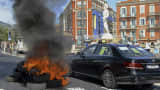 A taxi drives past burning tires during a national protest against car-sharing service Uber in Nice, France, June 25, 2015.