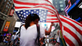 A woman walks with an American flag in Times Square, New York.