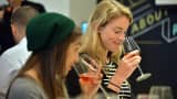 Elissa Garza, 25, of Boston, and Gabi Parsons, 24, of San Francisco (from left) sampled glasses of wine during a recent class that paired finance education with a wine tasting at the Society of Grownups, a financial education operation that uses a coffee shop and dinner club atmosphere to help attract millennials.