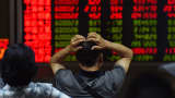 An investor looks at screens showing stock market movements at a securities company in Beijing.