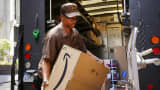A UPS worker carries an Amazon box to be delivered in New York in July.