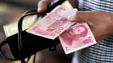 A customer holds a 100 Yuan note at a market in Beijing.