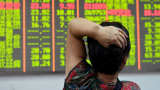 An investor looks at an electronic board showing stock information in Hangzhou, China.
