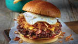 Applebee's all-day brunch burger with bacon, onions, a fried egg, hash browns, American cheese and ketchup piled high on a bun.