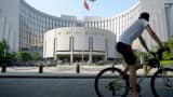 A man rides his bicycle past the People's Bank of China in Beijing.