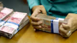 A clerk arranges bundles of Indonesian 100,000 rupiah banknotes at a currency exchange office in Jakarta, Indonesia.