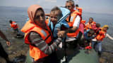 A Syrian refugee, from Kobani, carries her baby as she arrives with other Syrian refugees on a dinghy on the island of Lesbos, Greece August 23, 2015. Greece, mired in its worst economic crisis in generations, has been found largely unprepared for a mass influx of refugees, mainly Syrians. Arrivals have exceeded 160,000 this year, three times as high as in 2014.