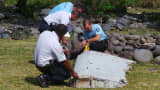 French gendarmes and police inspect a large piece of plane debris which was found on the beach in Saint-Andre, on the French Indian Ocean island of La Reunion, July 29, 2015. French prosecutor announced on Thursday that we can say with certainty that the wing part found on Saint-Andre beach was from missing Malaysia Airlines Flight MH370.