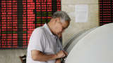 A stock investor monitors trading activity in a stock exchange in China.