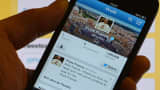 A man holds a smartphone showing Pope Francis' first tweet.