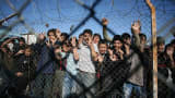 Immigrant minors peer out through the fence of an immigrant detention center in the village of Filakio, on the Greek-Turkish border.