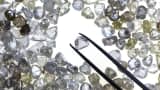 An uncut diamond is selected from a collection of colorless and colored diamonds on a sorting table at DTC Botswana, a unit of De Beers, in Gaborone, Botswana.