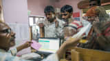 An employee serves customers inside a branch of Gramin Bank of Aryavat (GBA), sponsored by Bank of India, in the village of Khurana, Uttar Pradesh, India, on Monday, April 13, 2015.