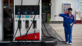 An employee directs a vehicle toward gas pumps at a China Petroleum & Chemical Corp. (Sinopec) gas station in the Zhujiang New Town district of Guangzhou, Guangdong Province, China.