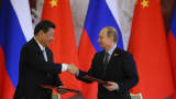 Russian President Vladimir Putin (R) shakes hands with Chinese President Xi Jinping.