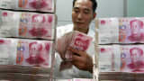 Chinese bank staff member counting stacks of 100-yuan notes at a bank in Huaibei, China.