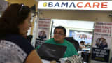 Martha Lucia sits with Rudy Figueroa, an insurance agent from Sunshine Life and Health Advisors, as she picks an insurance plan available in the third year of the Affordable Care Act at a store setup in the Mall of the Americas on Nov. 2, 2015, in Miami.