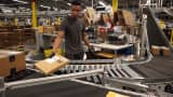 An Amazon.com worker sorts packages onto a conveyor belt at an Amazon fulfillment center in Tracy, California.