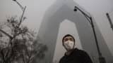 A Chinese man wears a protective face mask as he passes by the CCTV Headquarters on November 30, 2015, in Beijing, China.