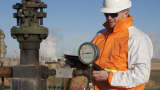 An oil worker checking a pumpjack.