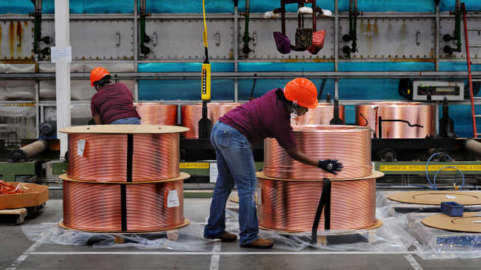 Factory workers secure large copper tube coils that will be wrapped and shipped out.