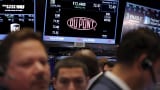 Traders work below a board displaying the DuPont logo on the floor of the New York Stock Exchange shortly after the opening bell in New York December 9, 2015.