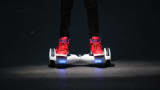 A youth poses as he rides a hoverboard, which is also known as a self-balancing scooter and balance board.